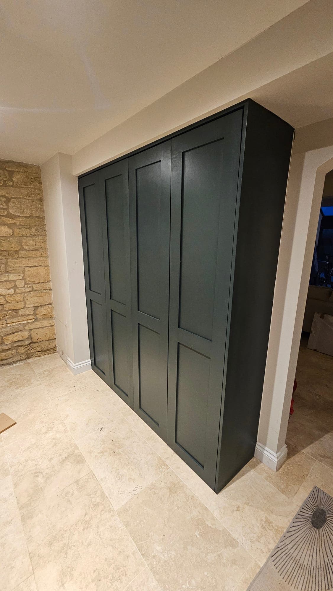 Fitted cupboard in deep green within a stone alcove