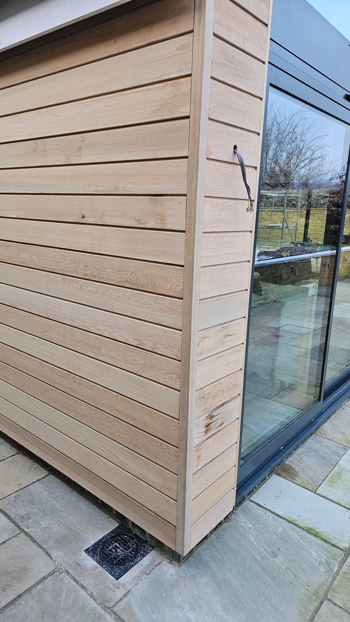 Oak cladding meeting the dark aluminium glazing