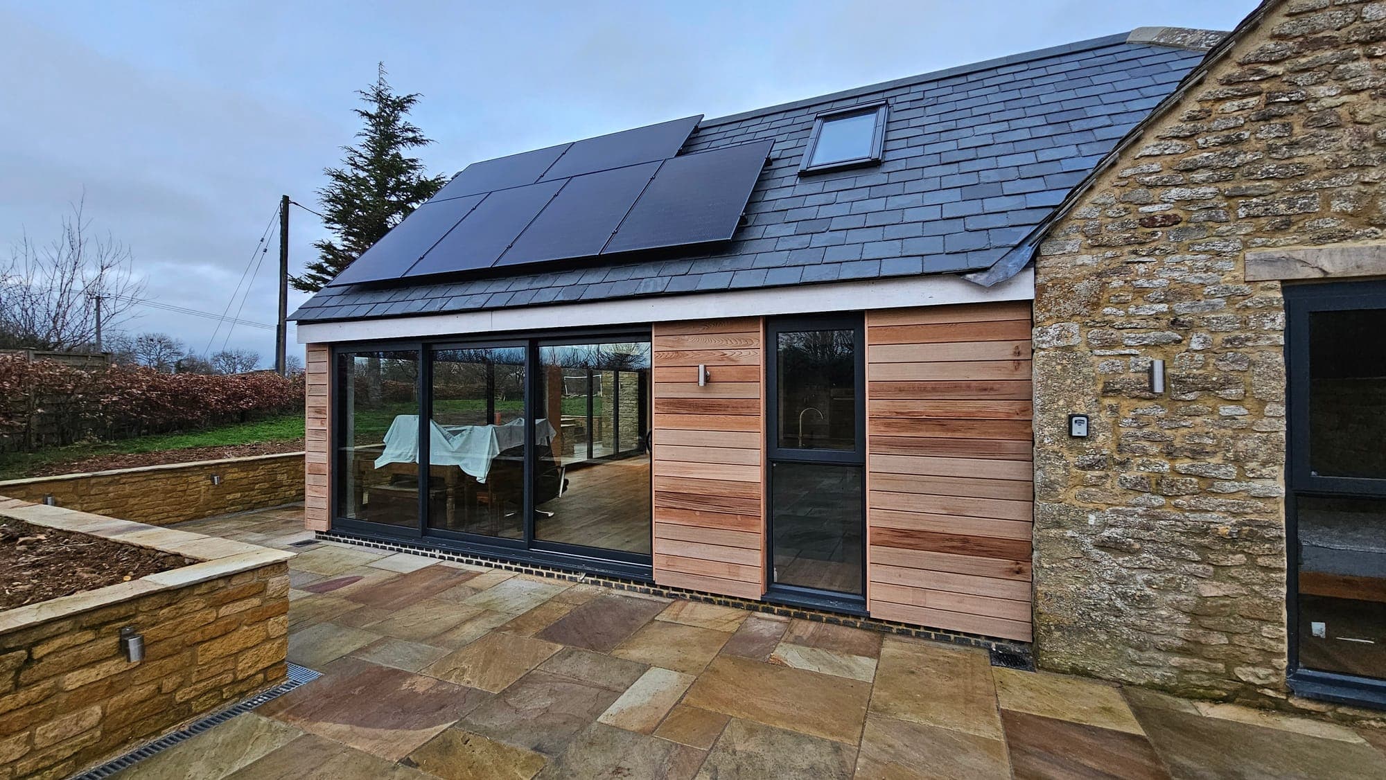 Garden elevation: stone house, oak extension and solar array
