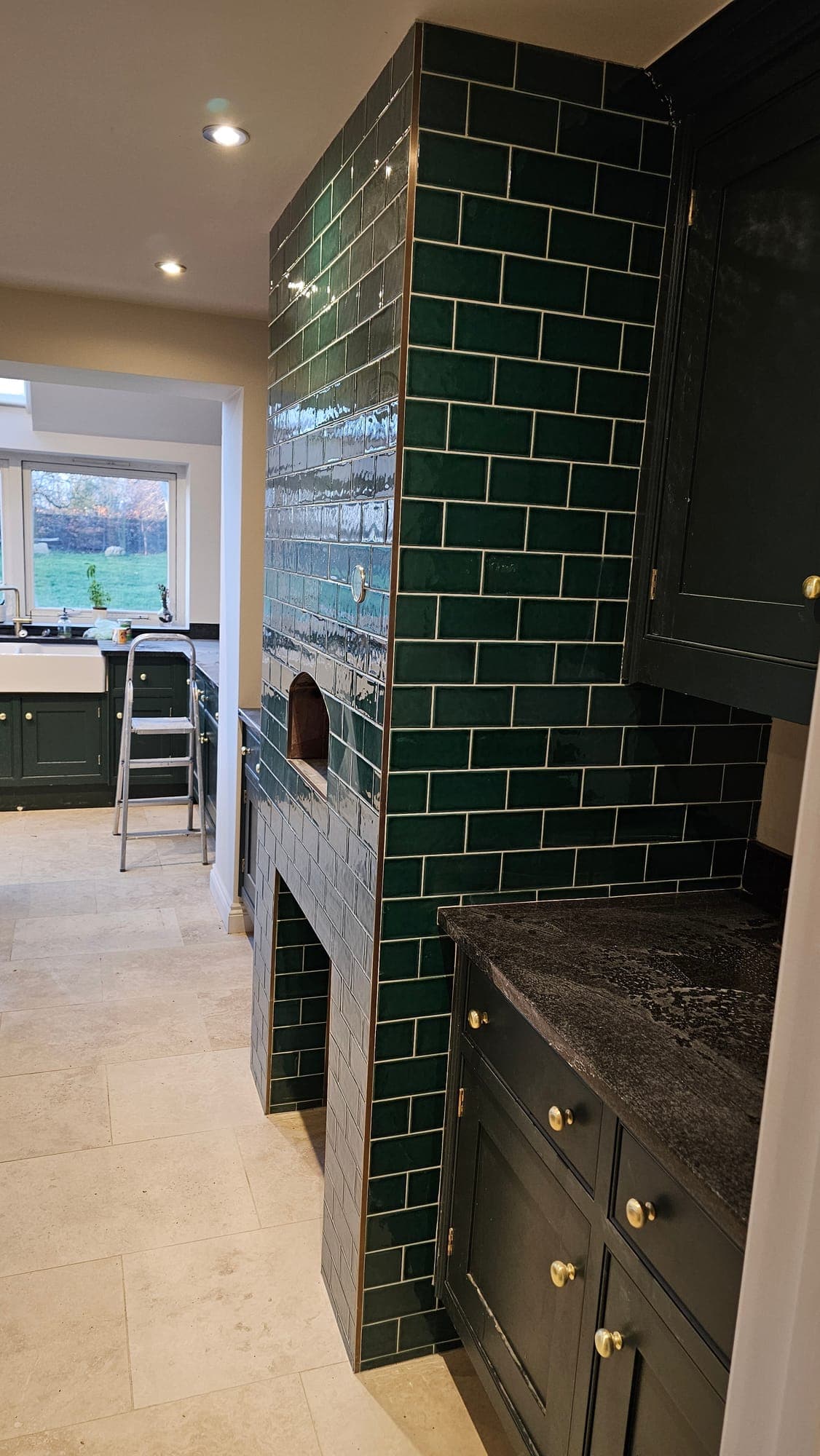 Green tiles going up around the range alcove